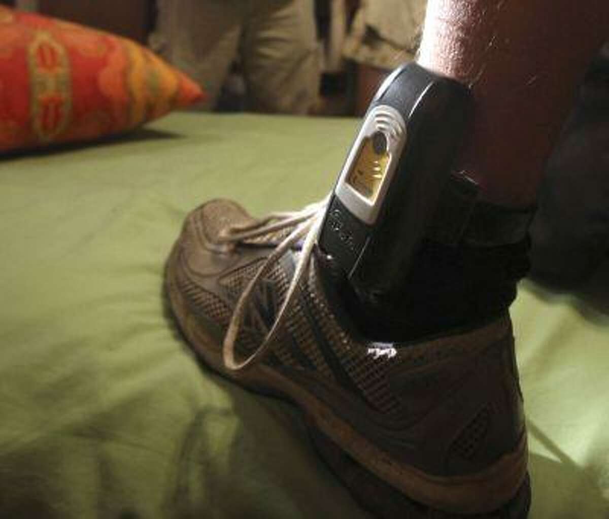 In this Aug. 3, 2009, file photo, Parole Agent Steve Nakamura uses a flashlight to inspect a GPS locater worn on the ankle of a parolee in Rio Linda, Calif.