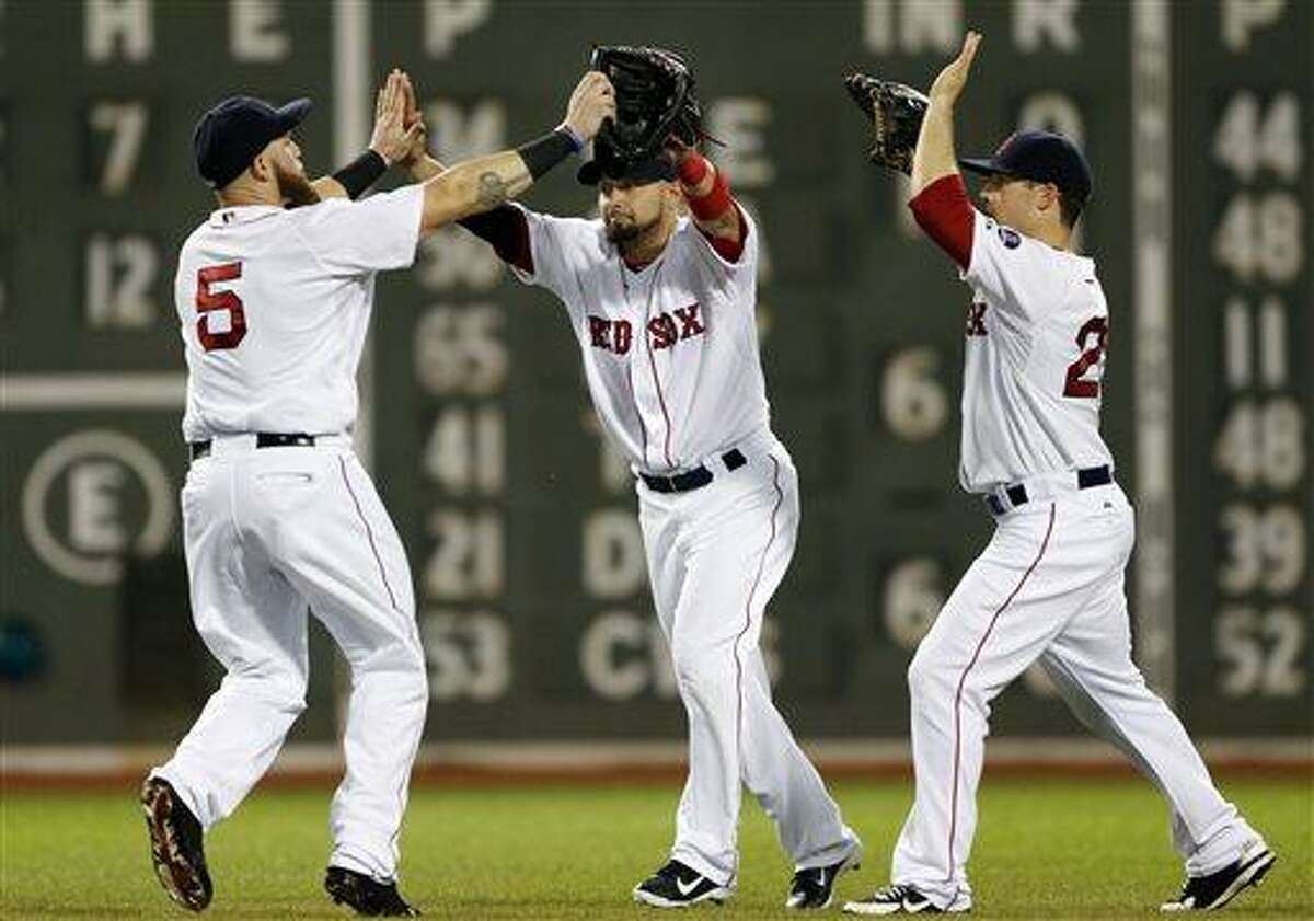 Boston Red Sox outfielders Jonny Gomes (5), Shane Victorino, middle, and Daniel Nava celebrate after the Red Sox defeated the Tampa Bay Rays 6-2 in a baseball game at Fenway Park in Boston Tuesday, July 23, 2013. (AP Photo/Elise Amendola)