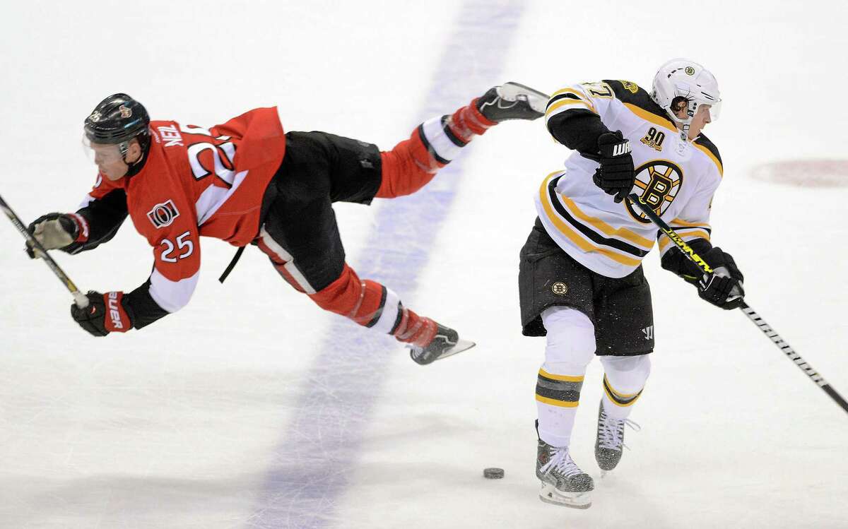 The Senators’ Chris Neil, left, falls after a collision with the Boston Bruins’ Torey Krug during the first period of Friday night’s game in Ottawa, Ontario.