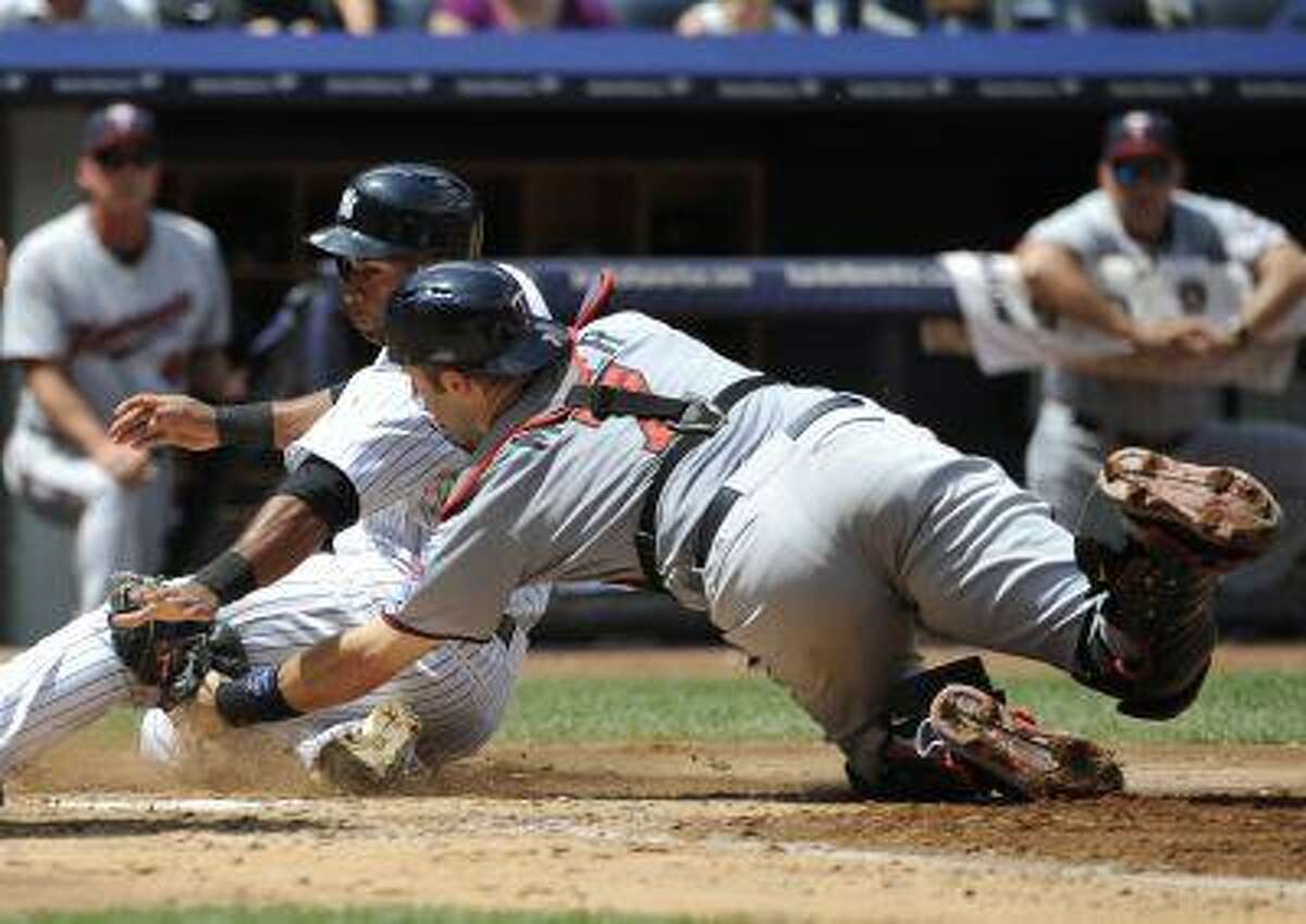 New York Yankees' Zoilo Almonte is tagged out at home plate by Minnesota Twins catcher Joe Mauer trying to score on Vernon Wells' fly ball in the third inning of a baseball game at Yankee Stadium on Sunday, July 14, 2013 in New York.