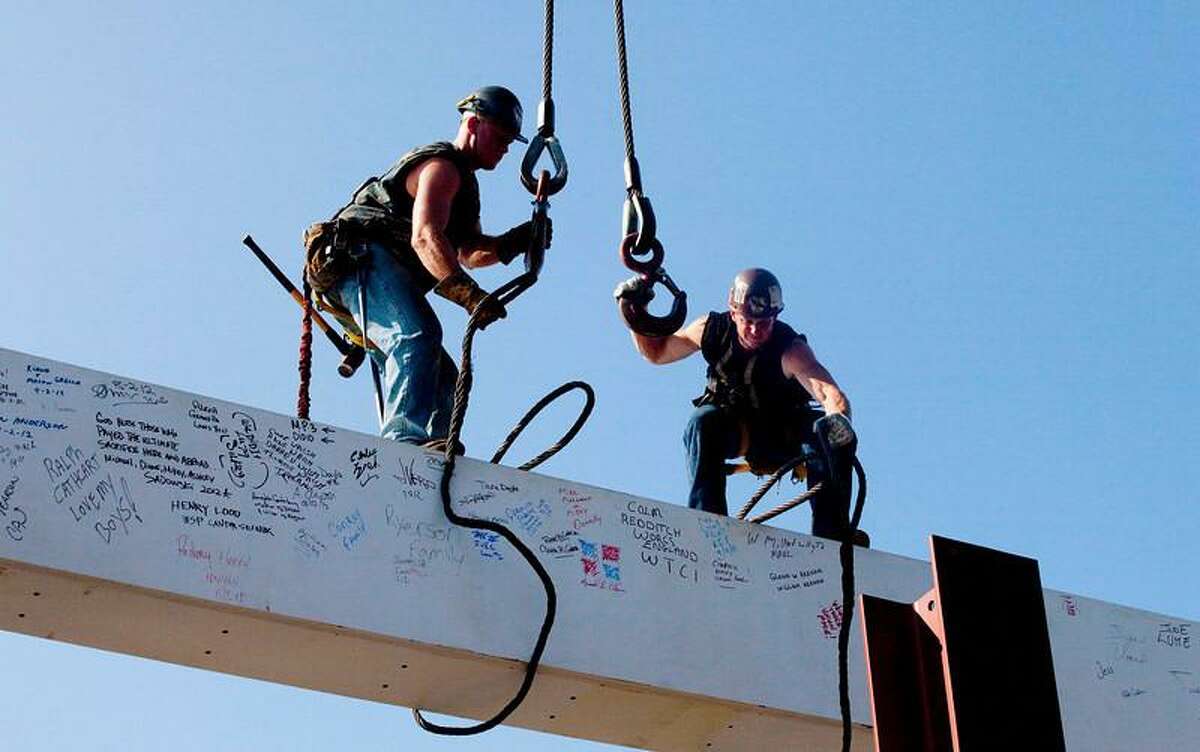 In this file photo of Aug. 2, 2012, ironworkers James Brady, left, and Billy Geoghan release the cables from a steel beam after connecting it on the 104th floor of One World Trade Center in New York. The beam was signed by President Barack Obama with the notes: "We remember," "We rebuild" and "We come back stronger!" during a ceremony at the construction site June 14. Also adorned with the autographs of workers and police officers at the site, the beam will be sealed into the structure of the tower, which is scheduled for completion in 2014. (AP Photo/Mark Lennihan, File)