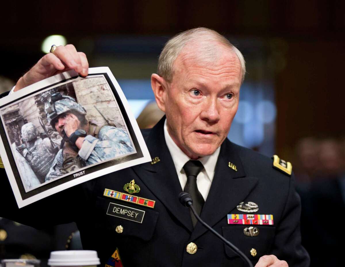 FILE - In this July 18, 2013, file photo, Gen. Martin Dempsey, chairman of the Joint Chiefs of Staff, holds up a photo of a deployed American soldier as he testifies before the Senate Armed Services Committee at his reappointment hearing, on Capitol Hill in Washington. The Obama administration is opposed to even limited U.S. military intervention in Syria because it believes rebels fighting the Assad regime wouldn't support American interests if they were to seize power right now, Dempsey said in a letter to a congressman obtained by The Associated Press. (AP Photo/J. Scott Applewhite, File)