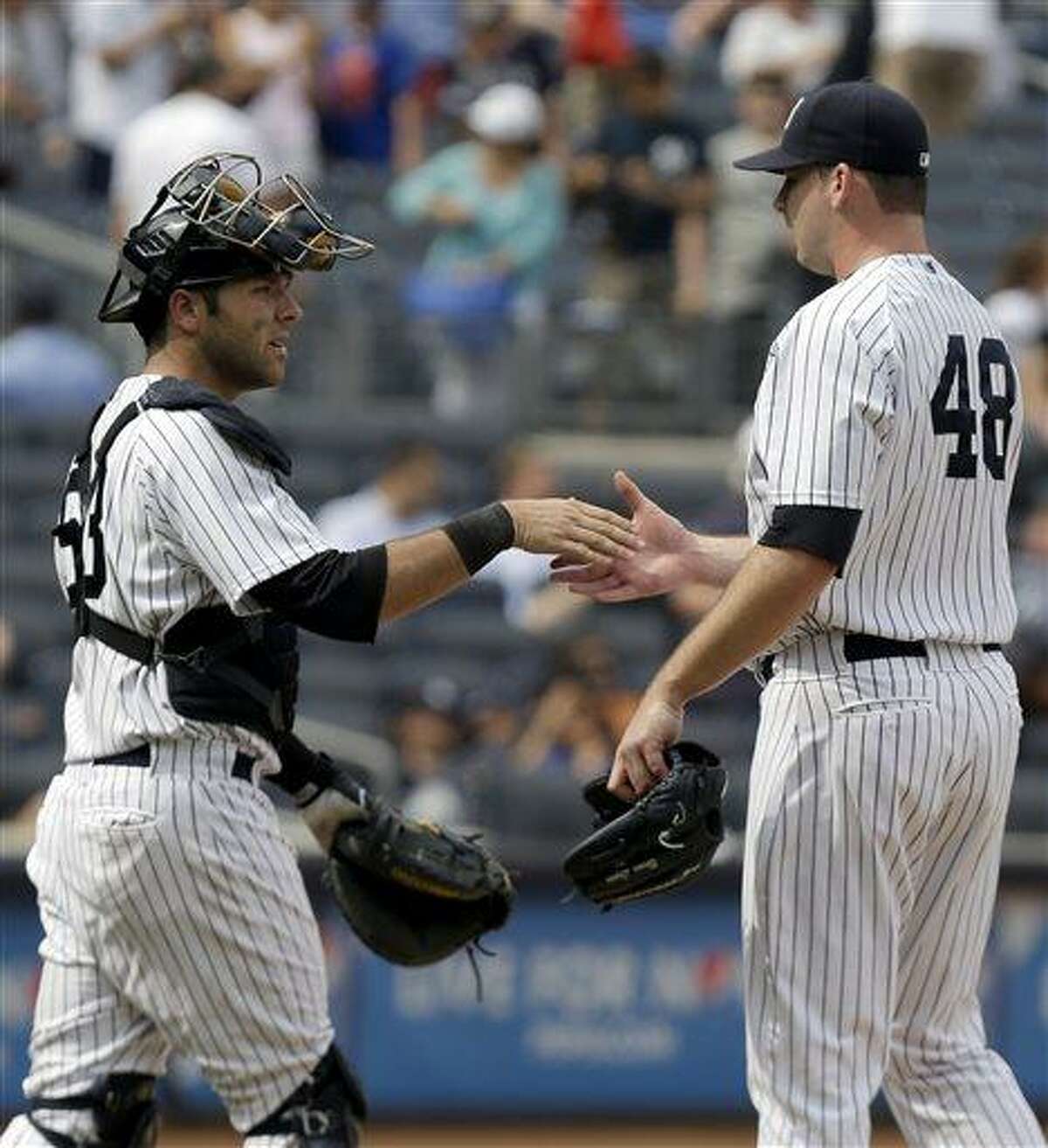 New York Yankees catcher Austin Romine, left, shakes hands with relief pitcher Boone Logan after defeating the Kansas City Royals in a baseball game at Yankee Stadium, Thursday, July 11, 2013, in New York. The Yankees won 8-4. (AP Photo/Seth Wenig)
