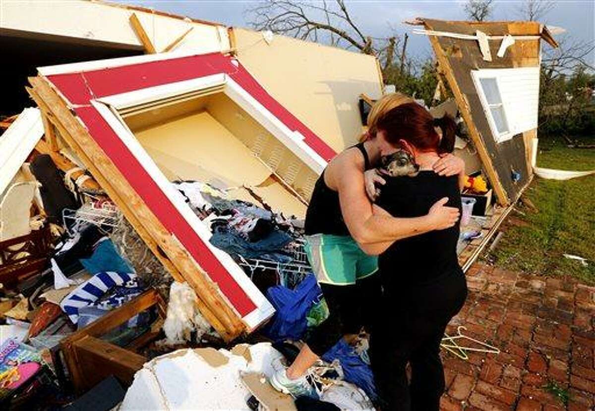 Alli Christian, left, returns Jessica Wilkinson's dog Bella to her after finding her among the wreckage of Wilkinson's home shortly after a tornado struck near 156th street and Franklin Road on Sunday, May 19, 2013 in Norman, Okla. No one was in the home when the storm struck. (AP Photo/The Oklahoman, Steve Sisney)