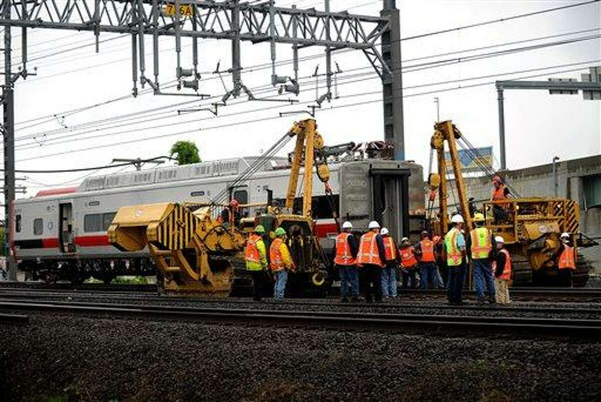 A derailed Metro-North rail car is hoisted back on to the tracks in Bridgeport. Conn. on Sunday, May 19, 2013. Crews will spend days rebuilding 2,000 feet of track, overhead wires and signals following the collision between two trains Friday evening that injured 72 people, Metro-North President Howard Permut said Sunday. (AP Photo/The Connecticut Post,Brian A. Pounds)
