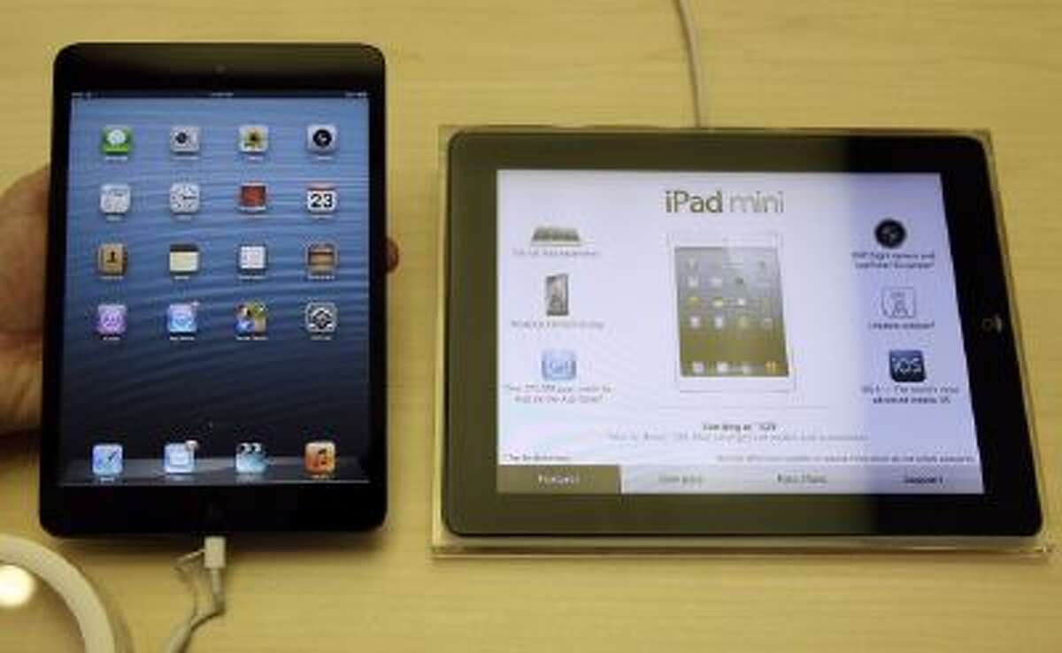 An Apple iPad mini, left, is held next to an iPad at an Apple store in San Francisco, Friday, Nov. 23, 2012.