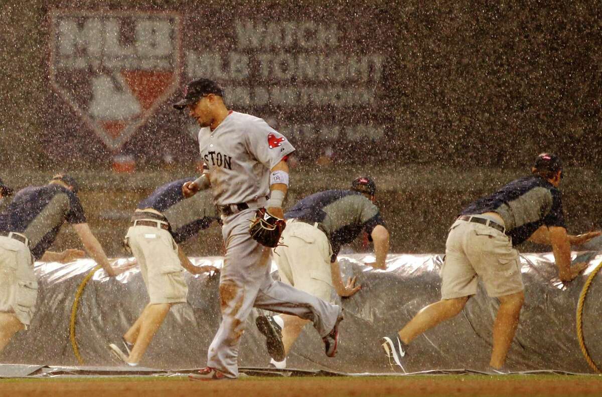 Boston Red Sox right fielder Shane Victorino (18) runs to the dugout as grounds crew tarp the field during a rain delay called during the seventh inning of a baseball game against the Minnesota Twins, Sunday, May 19, 2013, in Minneapolis. (AP Photo/Genevieve Ross)