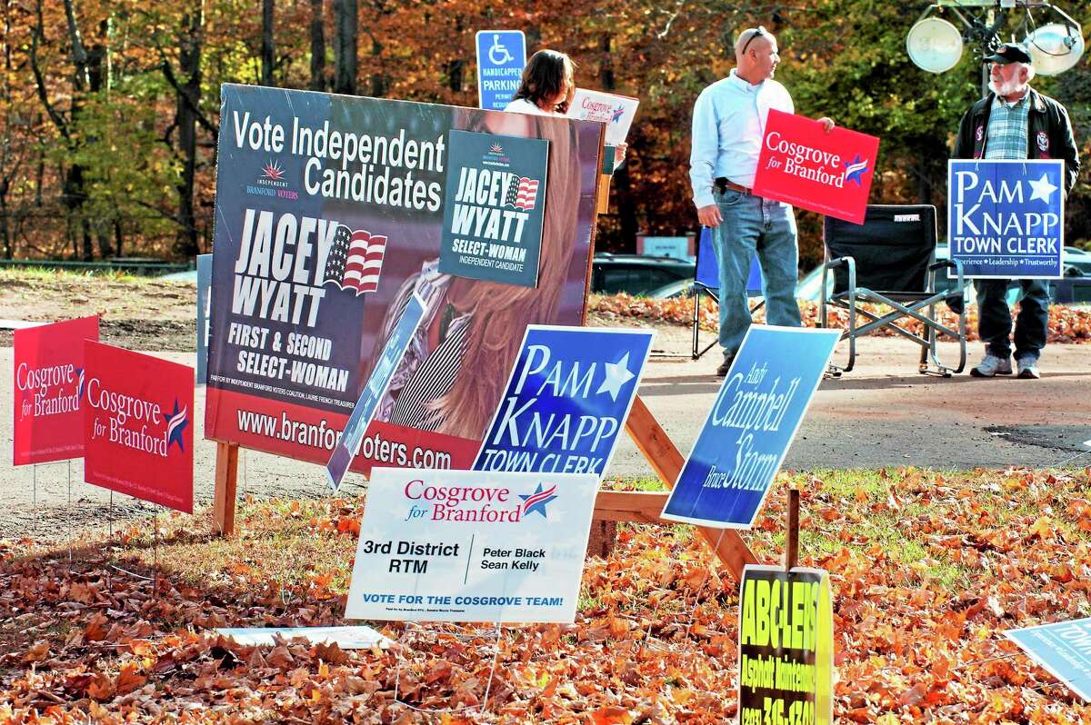 Hunter Kelly, Sean Kelly and Ted Aub hold signs promoting their favored canddiates in front of the 3rd Voting District in Branford Tuesday.