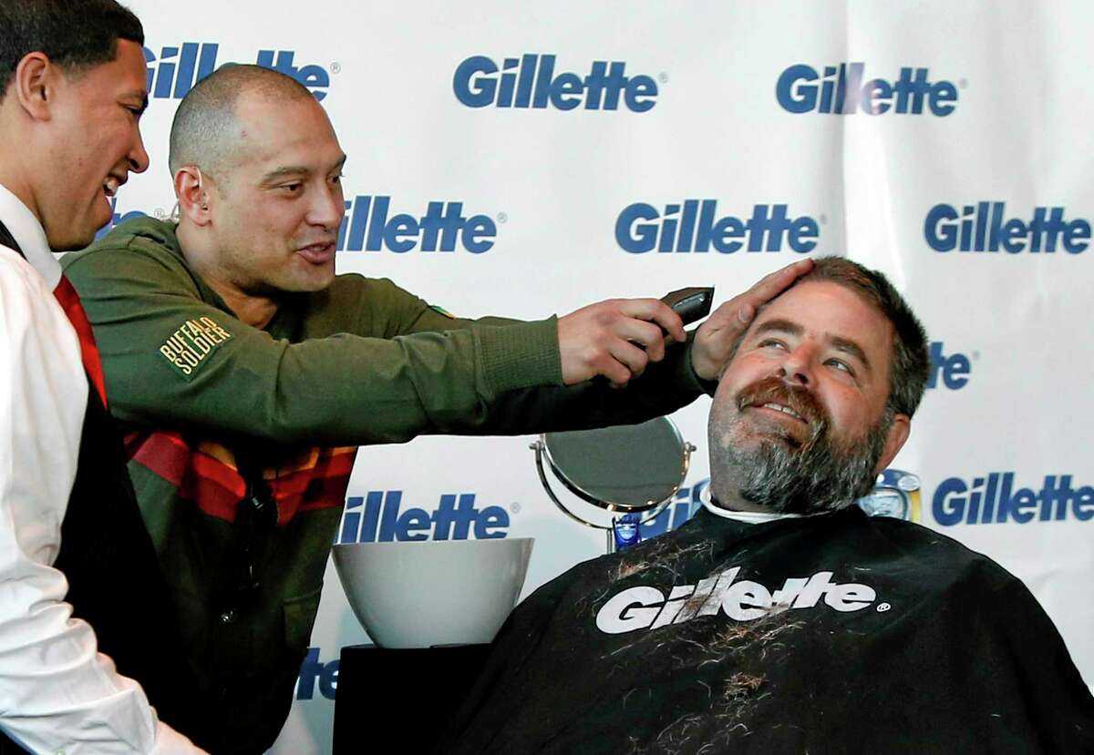 Shane Victorino, center, kids around with a razor as Boston Police Officer Steve Horgan, right, is shaved for One Fund Boston, the Boston Marathon charity for bombing victims, during a shave-off in Boston, Monday.