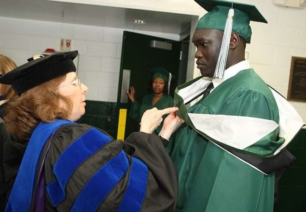 PHOTO BY JOHN HAEGER @ ONEIDAPHOTO ON TWITTER/ONEIDA DAILY DISPATCH Prof Roberta Sloan helps Deng Kiir get ready before the start of the 102nd commencement ceremony at Morrisville State College on Saturday, May 18, 2013. Deng Kiir is one of the lost boys of the Sudan, will receive his bachelor degree from the School of Business.
