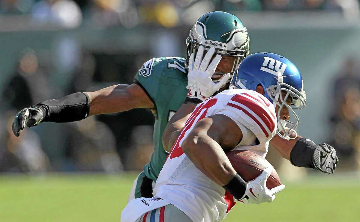 The Giants’ Victor Cruz runs the ball against the defense of Eagles’ Bradley Fletcher during first half of Sunday’s game.