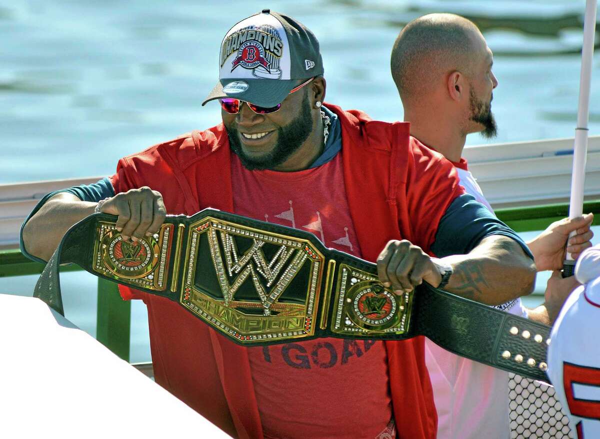 Red Sox designated hitter David Ortiz holds up a championship belt as he and his teammates ride on a duck boat on Saturday on the Charles River in Boston during a rolling parade celebrating the team’s World Series title.