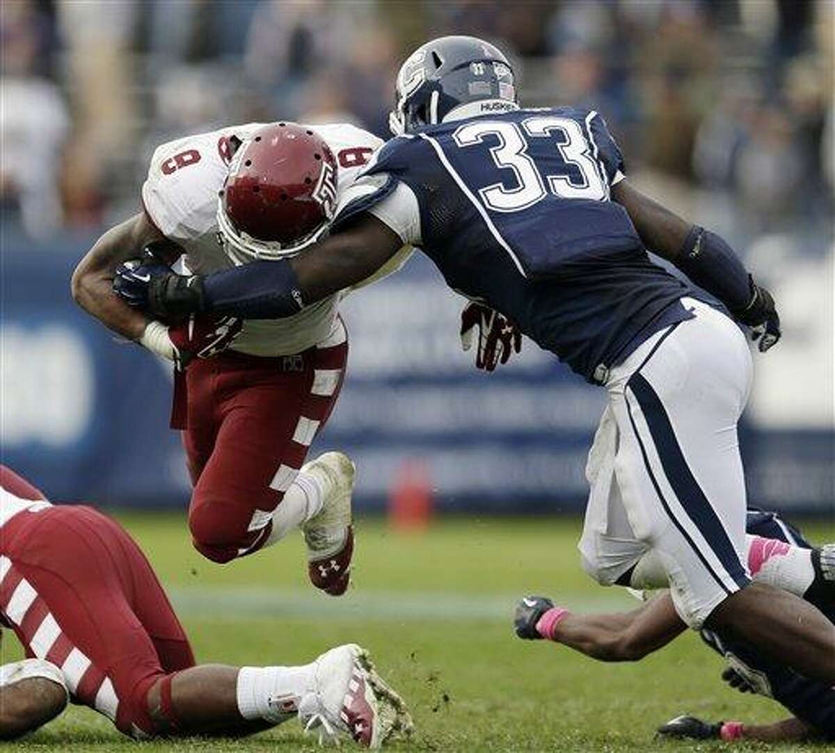 Connecticut linebacker Yawin Smallwood (33) tackles Temple running back Montel Harris (8) in overtime during an NCAA college football game in East Hartford, Conn., Saturday, Oct. 13, 2012. Temple won 17-14. (AP Photo/Michael Dwyer)