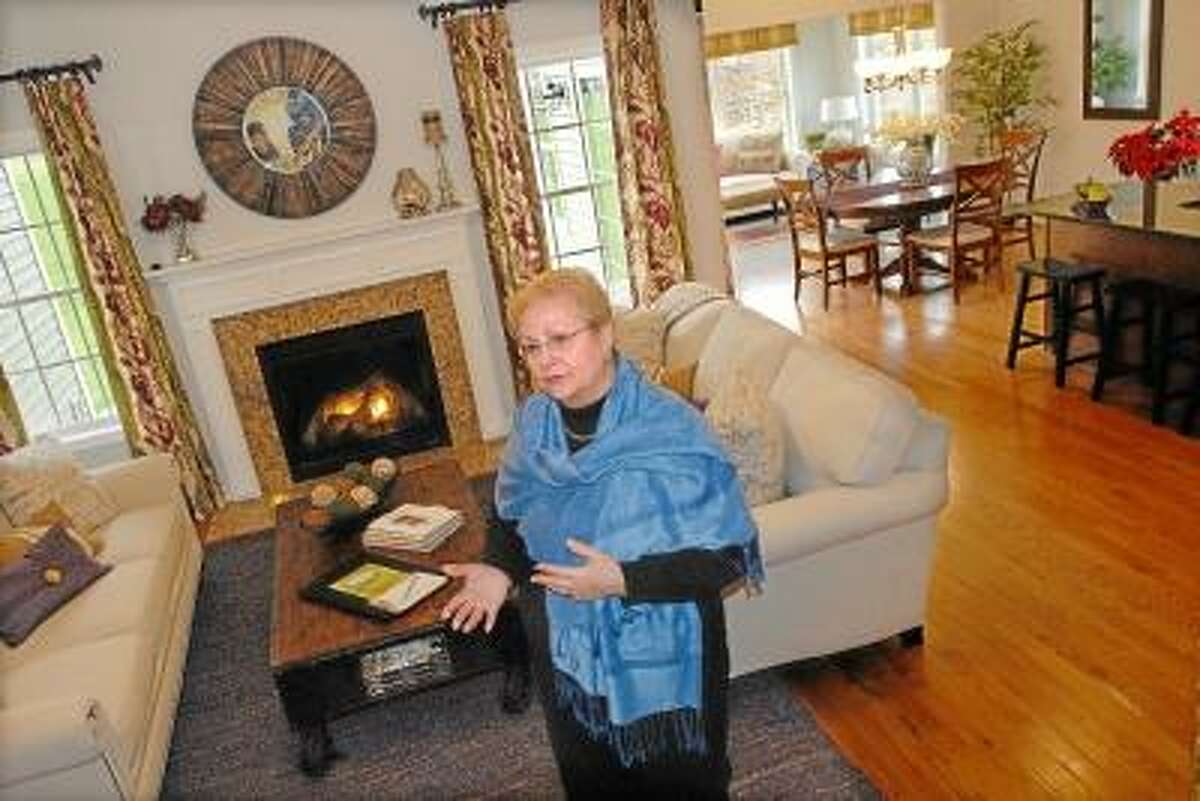 Catherine Avalone/The Middletown Press Marie Coughlin, a resident and realtor at Sonoma Woods, an over 55 active adult community on Westfield Street in Middletown stands in the livingroom of the Zinfandel cape, a 1,974 square foot home with has 2 bedrooms and 3 bathrooms and sells for $349,900.