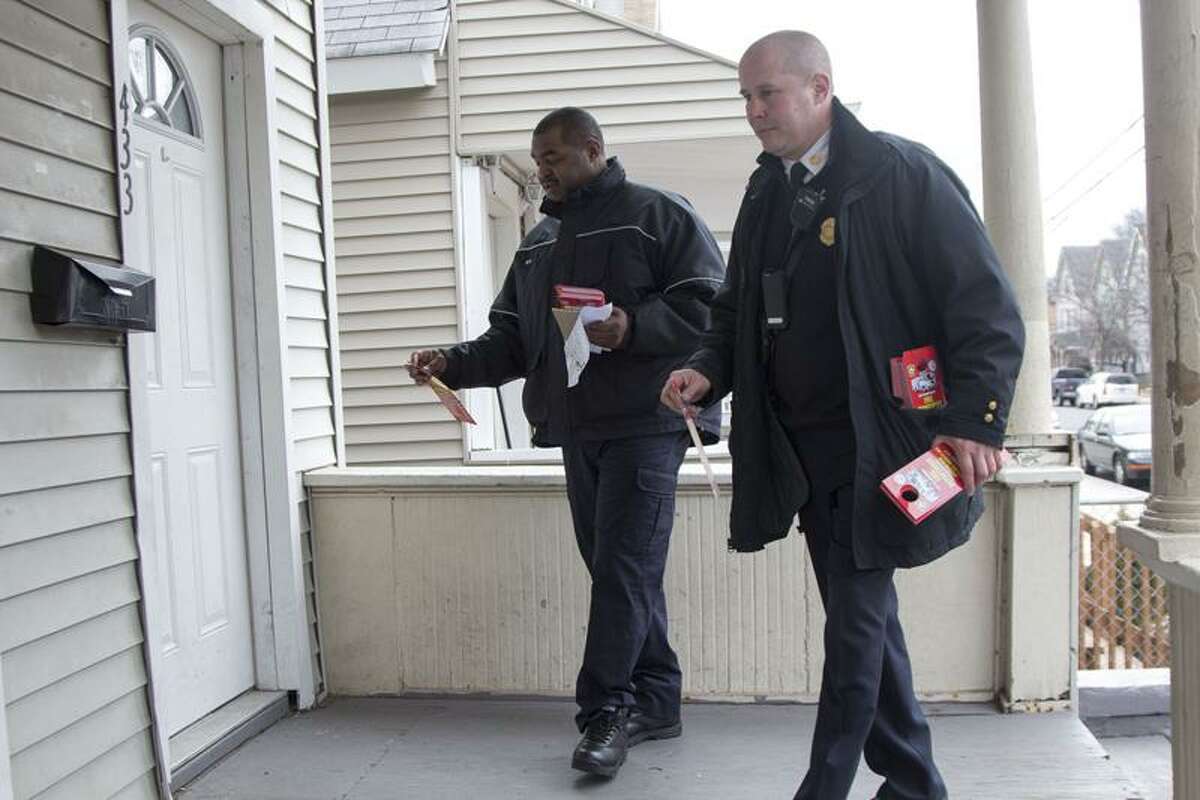 New Haven Fire Department Assistant Chief Patrick Egan and firefighter Michael Neal hang recruitment flyers on doors in the Hill Fire District on Tuesday. The department is looking to hire between 80-100 entry-level firefighter positions out of the next recruitment class. Photo by Rich Scinto/Register