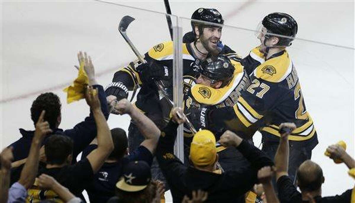 Boston Bruins left wing Brad Marchand, center, is congratulated by teammates Dougie Hamilton (27) and Zdeno Chara, left, following his game-winning goal against New York Rangers goalie Henrik Lundqvist during overtime in Game 1 of an NHL hockey playoffs Eastern Conference semifinal game in Boston, Thursday, May 16, 2013. The Bruins won 3-2. (AP Photo/Charles Krupa)