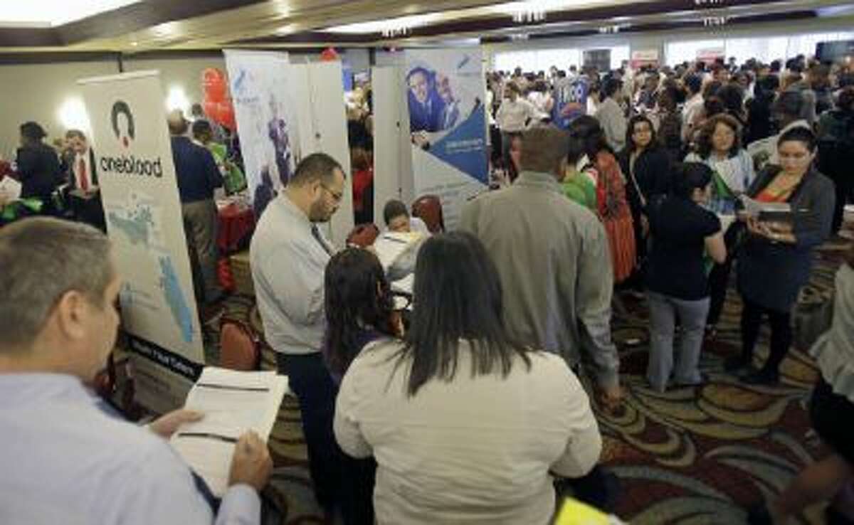 This Aug. 14, 2013 file photo shows job seekers checking out companies at a job fair in Miami Lakes, Fla.