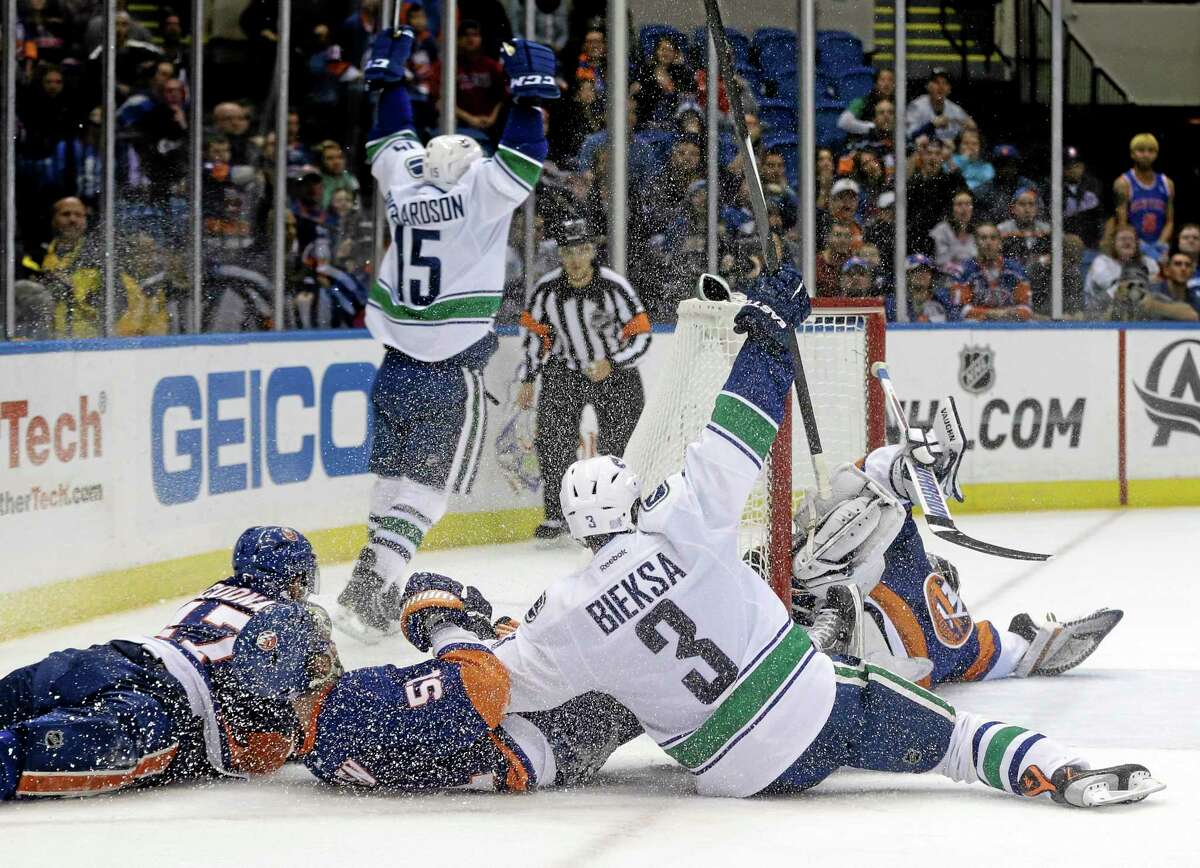 The Vancouver Canucks’ Brad Richardson (15) and Kevin Bieksa celebrate after Richardson scored during overtime Tuesday night against the Islanders in Uniondale, N.Y. The Canucks won the game 5-4.