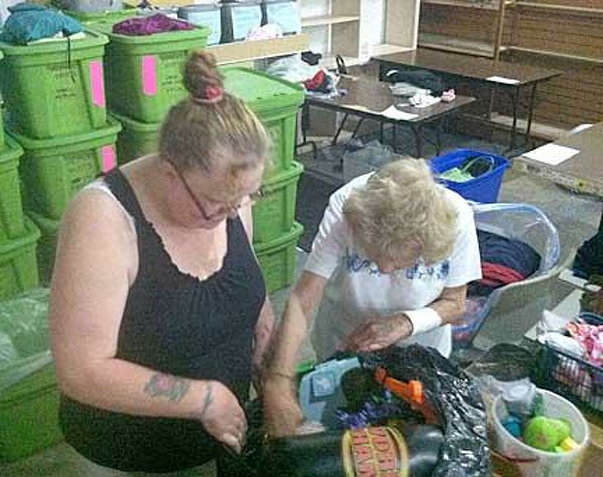 Volunteers Tracy Robertson, left, and Bea Leonard sort donations at Church on the Rock this morning. (Dispatch Photo by Nick Will)