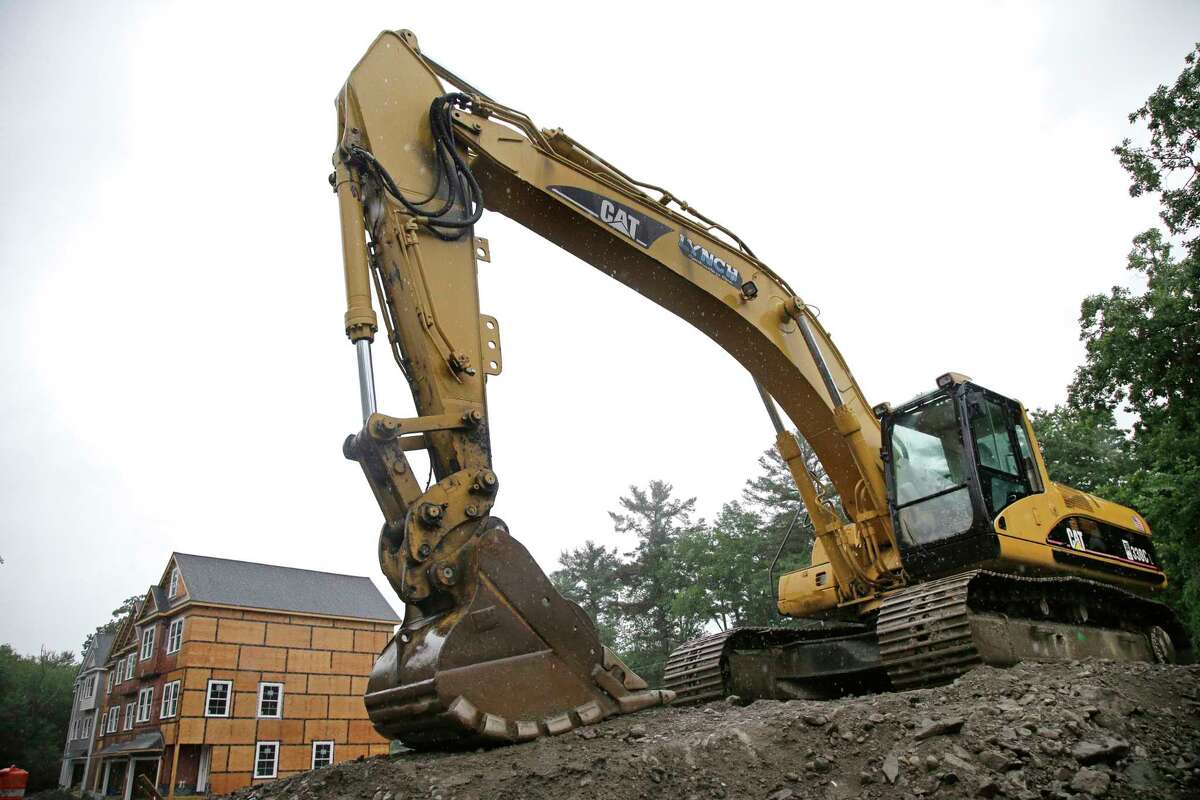 A Caterpillar excavator is on a housing construction site in North Andover, Mass. Caterpillar boosted its full-year forecast as ordering activity picked up.