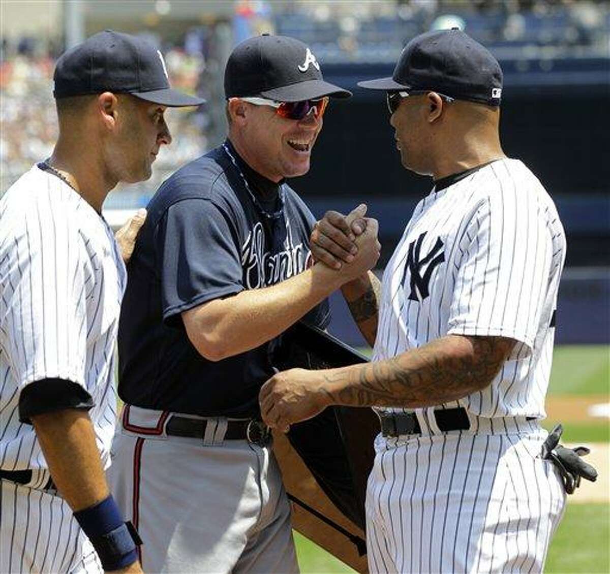 New York Yankees' Derek Jeter, left, watches as New York Yankees' Andruw Jones, right, congratulates Atlanta Braves' Chipper Jones, after presenting him with third base from Tuesday night's game, before the two teams faced off in a baseball game at Yankee Stadium in New York, Wednesday, June 20, 2012. Jones is retiring at the end of the season. (AP Photo/Kathy Willens)