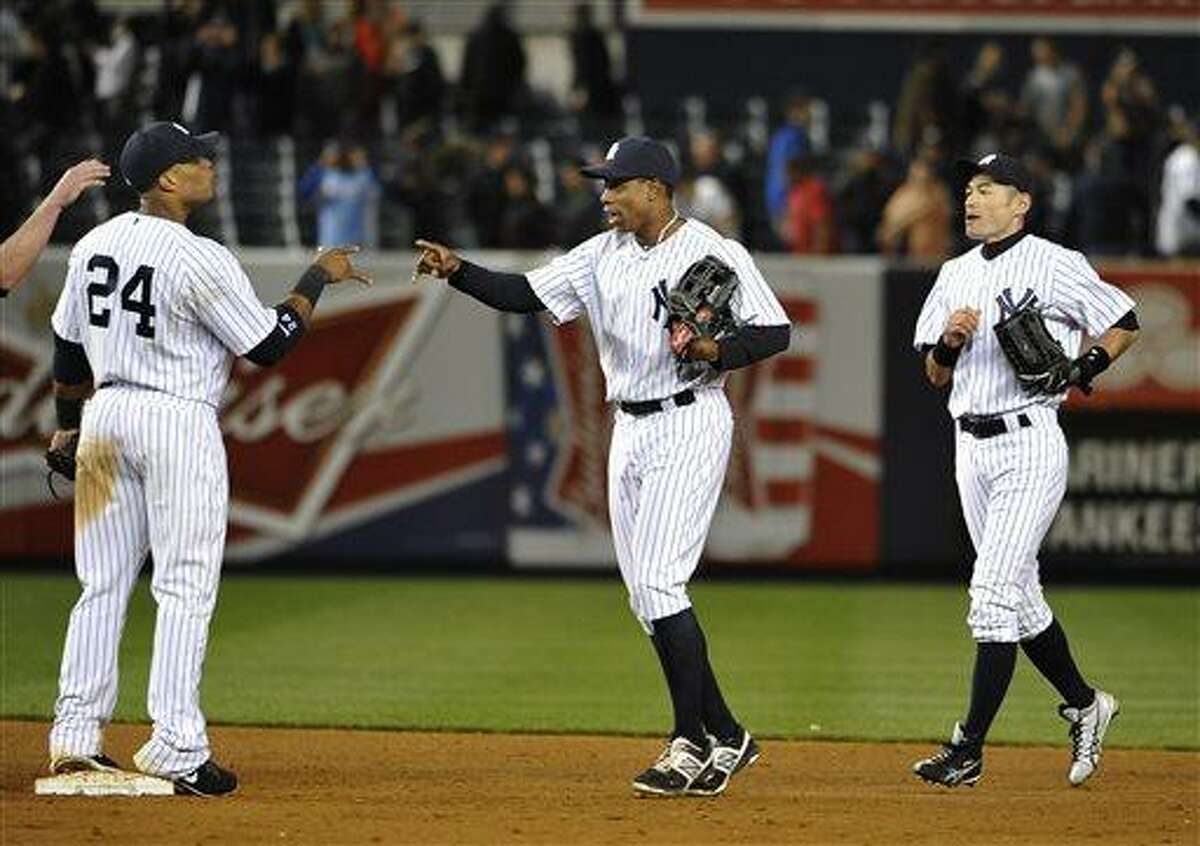 New York Yankees' Curtis Granderson, center, followed by Ichiro Suzuki, celebrates the Yankees' 4-3 win over the Seattle Mariners with Robinson Cano (24) following a baseball game at Yankee Stadium on Tuesday, May 14, 2013, in New York. (AP Photo/Kathy Kmonicek)