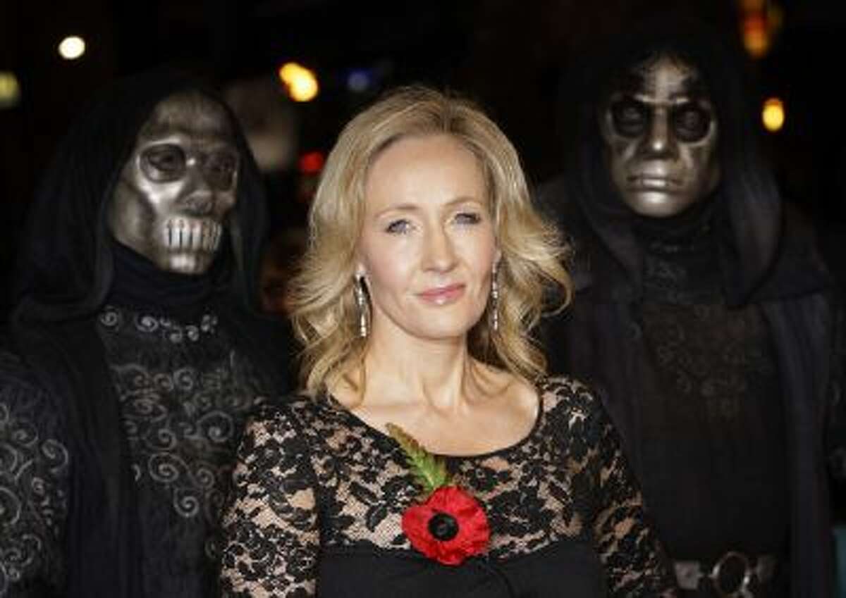 British author J K Rowling arrives at a cinema in London's Leicester Square for the World Premiere of Harry Potter and the Deathly Hallows Part 1, as masked actors stand behind, Nov. 11, 2010.