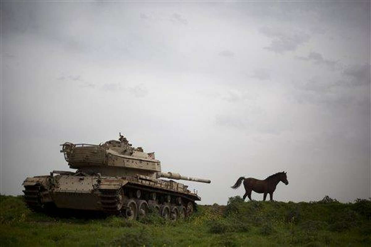 A horse runs in a pasture next to an old Israeli tank in the Israeli-controlled Golan Heights on the border with Syria, Friday, March 8, 2013. Israel captured the Golan from Syria in 1967 Mideast war. (AP Photo/Ariel Schalit)