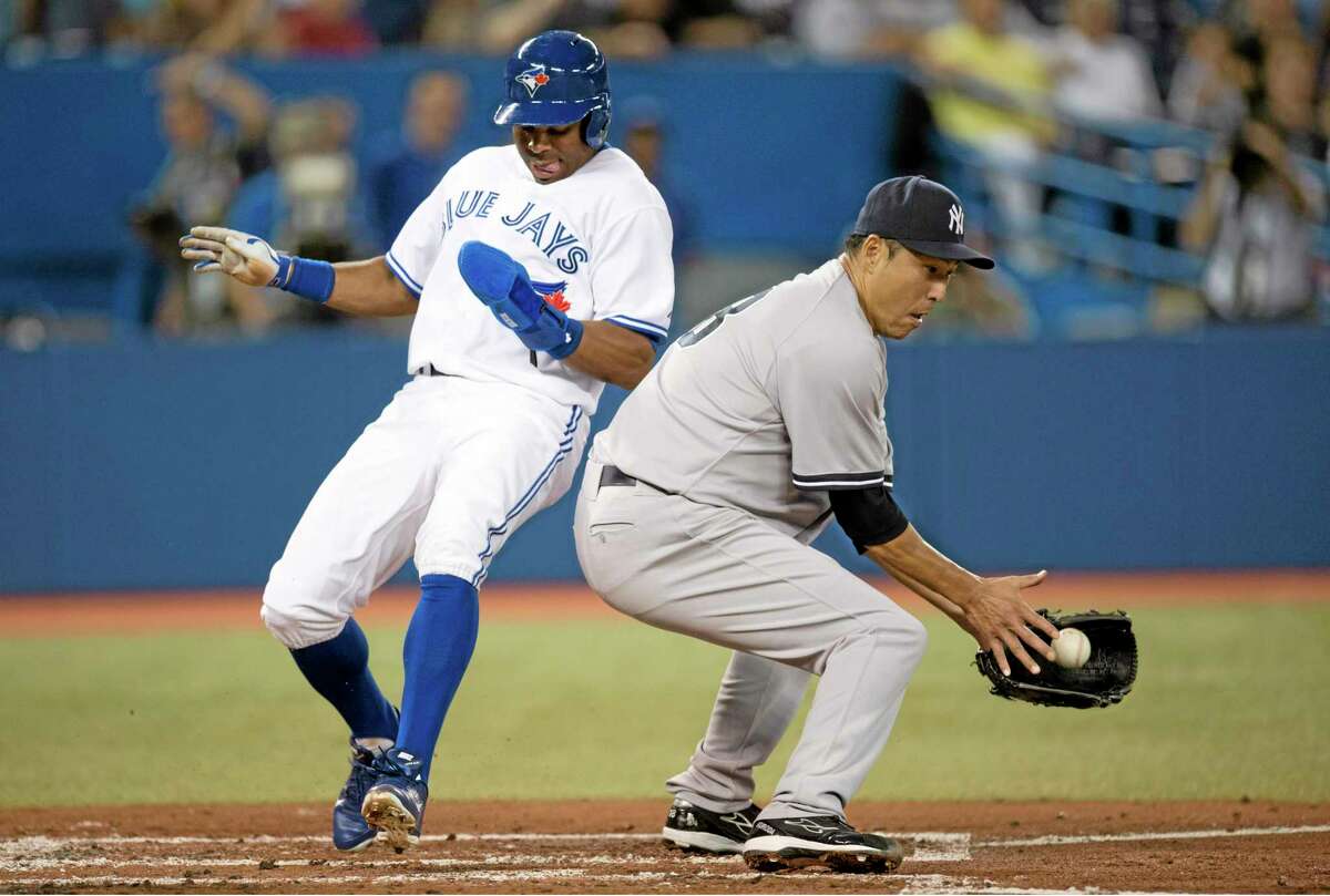 Toronto Blue Jays’ Rajai Davis, left, scores behind New York Yankees pitcher Hiroki Kuroda during first-inning action in Toronto.
