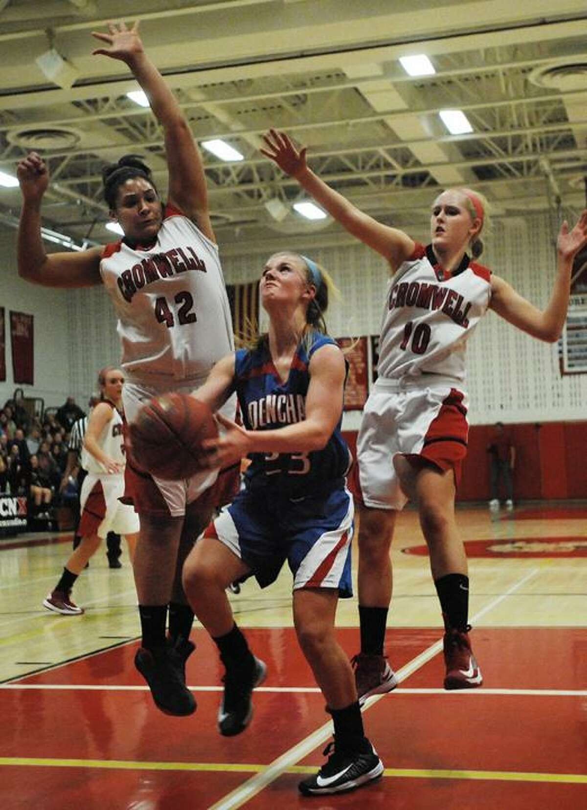 Catherine Avalone/The Middletown Press Cromwell's Mya Villard (42) and Emily Appleby (10) defend Coginchaug's Kim Romanoff as she drives in the paint Friday night in Cromwell. Cromwell defeated Coginchaug 45-30.