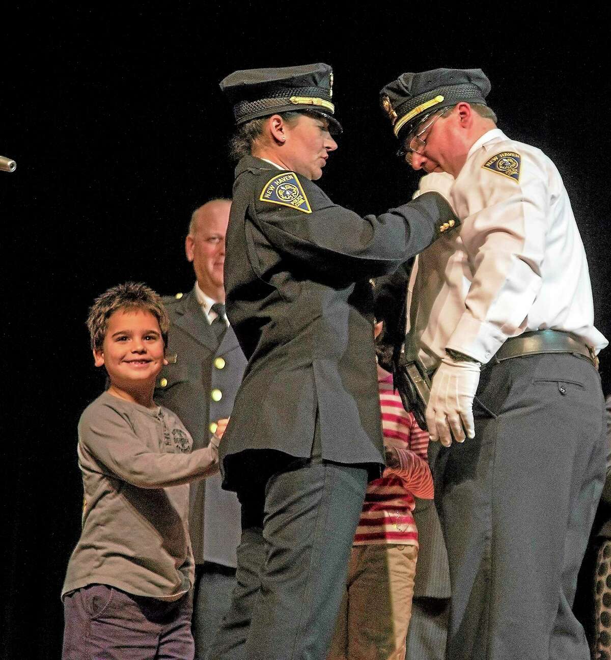 Danny Johnson, 8, beams as his mother, New Haven police Lt. Julie Johnson, pins a badge on Lt. Herb Johnson during Friday night’s New Haven police promotion ceremony.