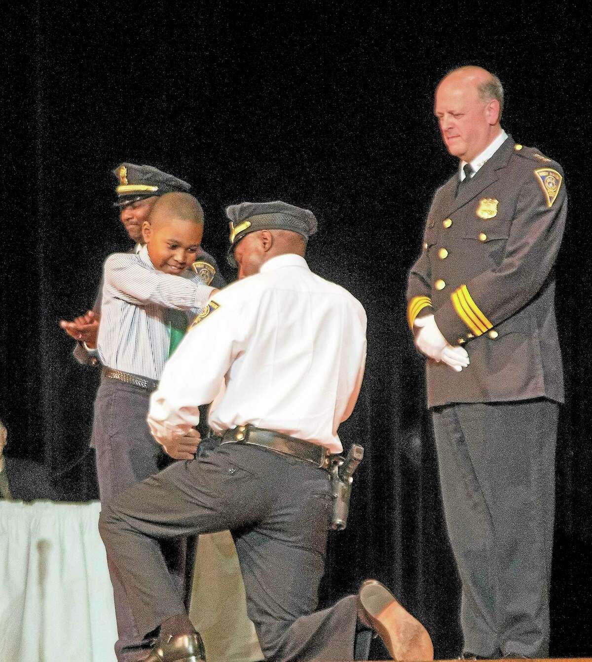 Sanderson Campbell pins a badge on his father, Lt. Anthony Campbell, during Friday night’s New Haven police promotion ceremony.