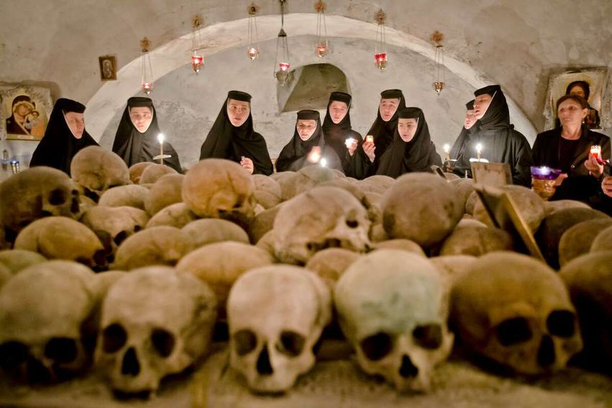 Romanian orthodox nuns sing in the ossuary at the Pasarea monastery, outside Bucharest, Romania, Sunday, May 5, 2013, during the Easter Religious service. The ossuary, containing mostly remains of the nuns that lived at the monastery is briefly opened on Easter night. (AP Photo/Vadim Ghirda)