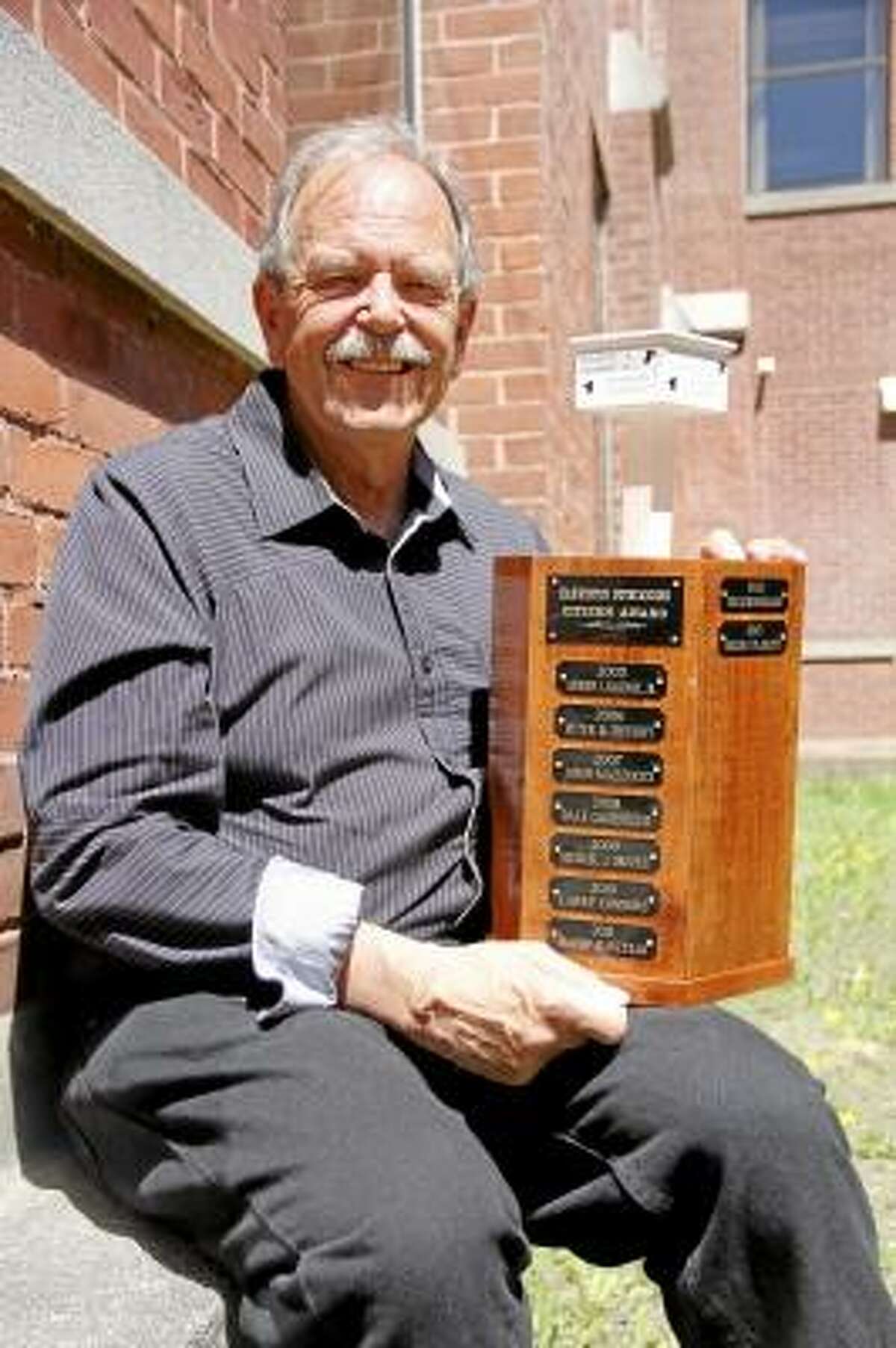 Roger P. Plaskett poses with the Harwinton Outstanding Citizen Award on Wednesday, May 1, 2013 in Torrington. Plaskett was named the 2013 recipient of the award in February, and had a banquet in his honor on April 26. The award is hand-crafted from Harwinton cherry wood and was designed by 2010 winner Larry Connors. It's the second incarnation of the award after the first one, which was first handed in 1975, filled up. (ESTEBAN L. HERNANDEZ/REGISTER CITIZEN)