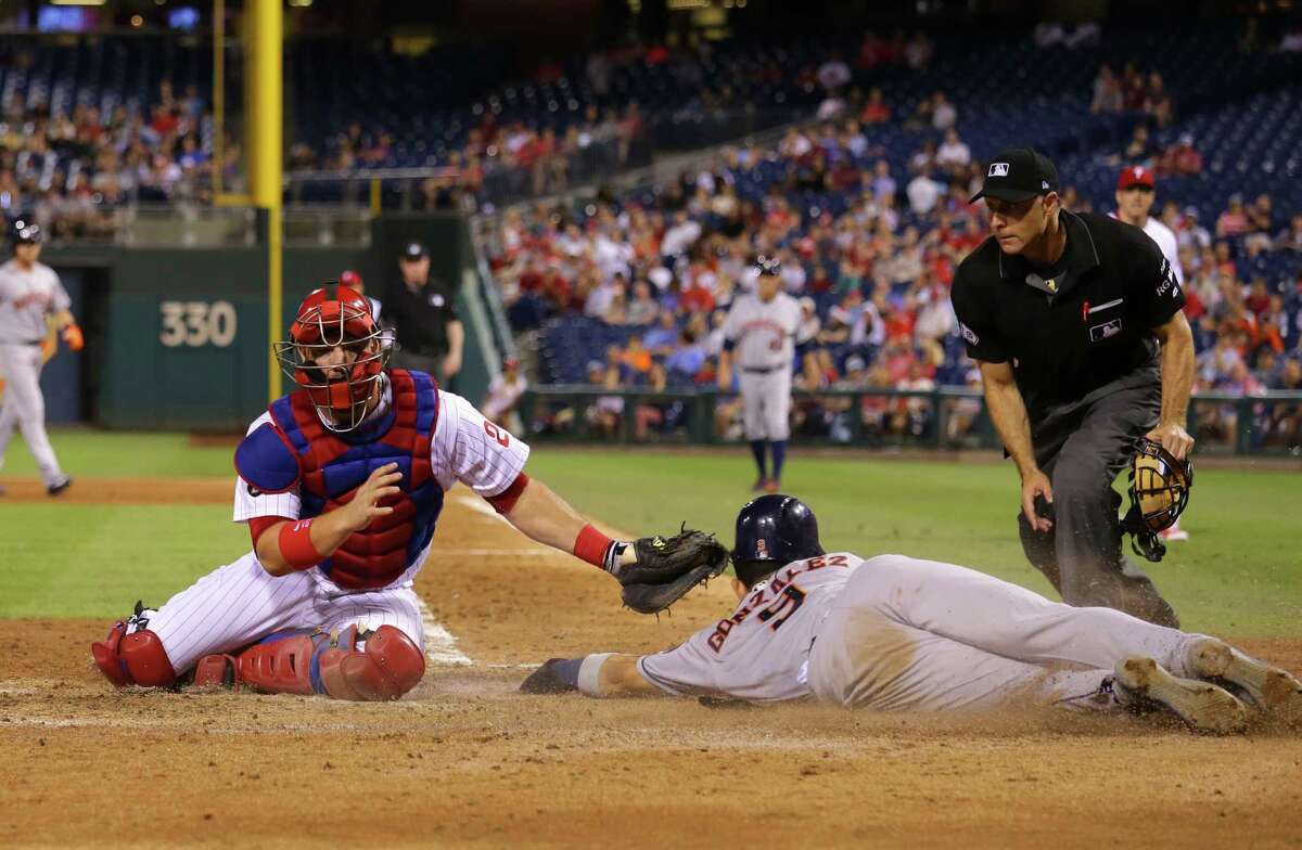 Marwin Gonzalez makes a deft slide around Phillies catcher Cameron Rupp to score in the sixth inning.