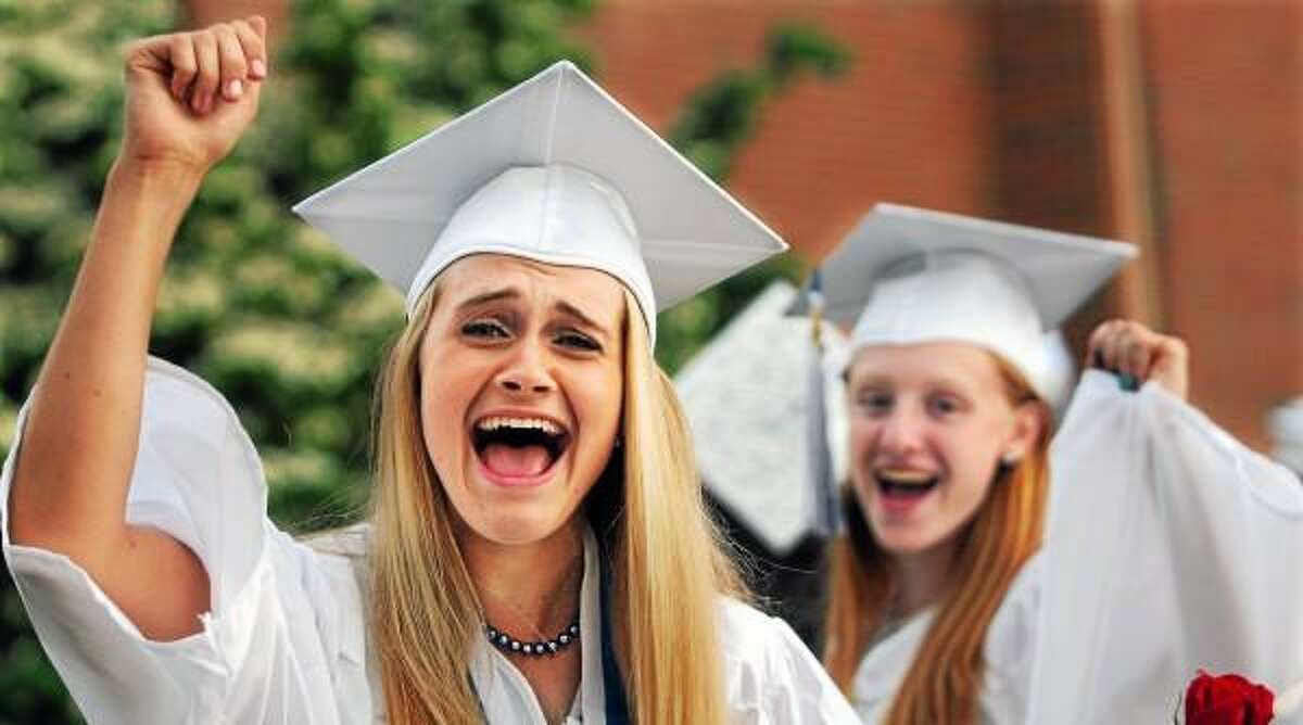 Catherine Avalone/The Middletown Press Coginchaug Class President Lauren Trombetta and Natalie Swanson pump their fists marching from the school cafeteria to the Julian B. Thayer Auditorium Tuesday night at graduation.