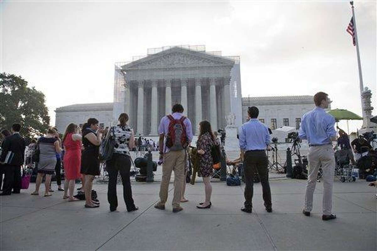 FILE - This June 24, 2013 file photo shows people waiting outside the Supreme Court in Washington as key decisions are expected to be announced. The Supreme Court said Tuesday that a key provision of the landmark Voting Rights Act cannot be enforced until Congress comes up with a new way of determining which states and localities require close federal monitoring of elections. (AP Photo/J. Scott Applewhite, File)