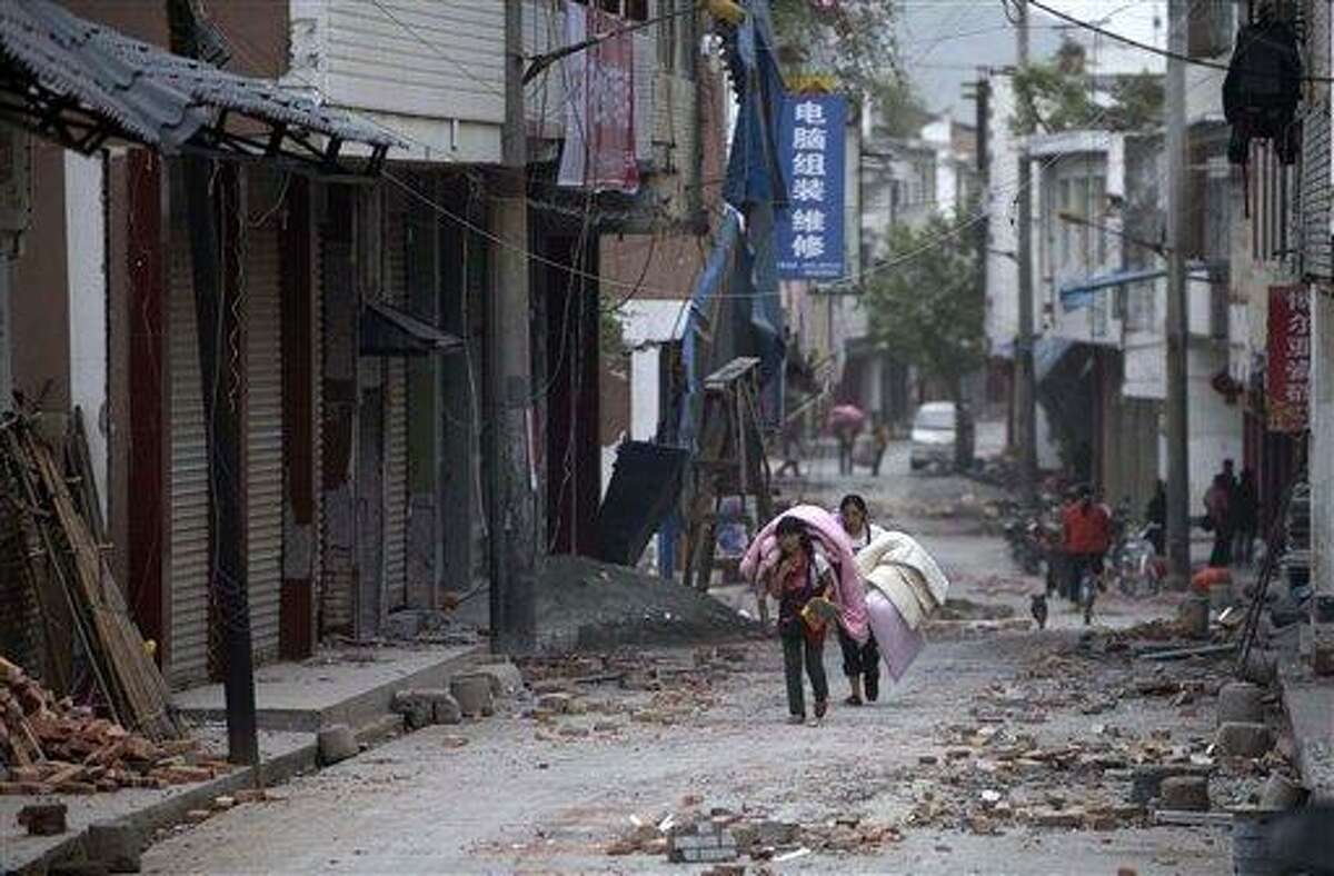 In this photo released by China's Xinhua news agency, people carrying their belongings walk in quake-damaged Gucheng Village, Longmen Township, Lushan County, southwest China's Sichuan Province, Saturday, April 20, 2013. A powerful earthquake struck the steep hills of Sichuan province Saturday, nearly five years after a devastating quake wreaked widespread damage across the region. (AP Photo/Xinhua, Fei Maohua) NO SALES