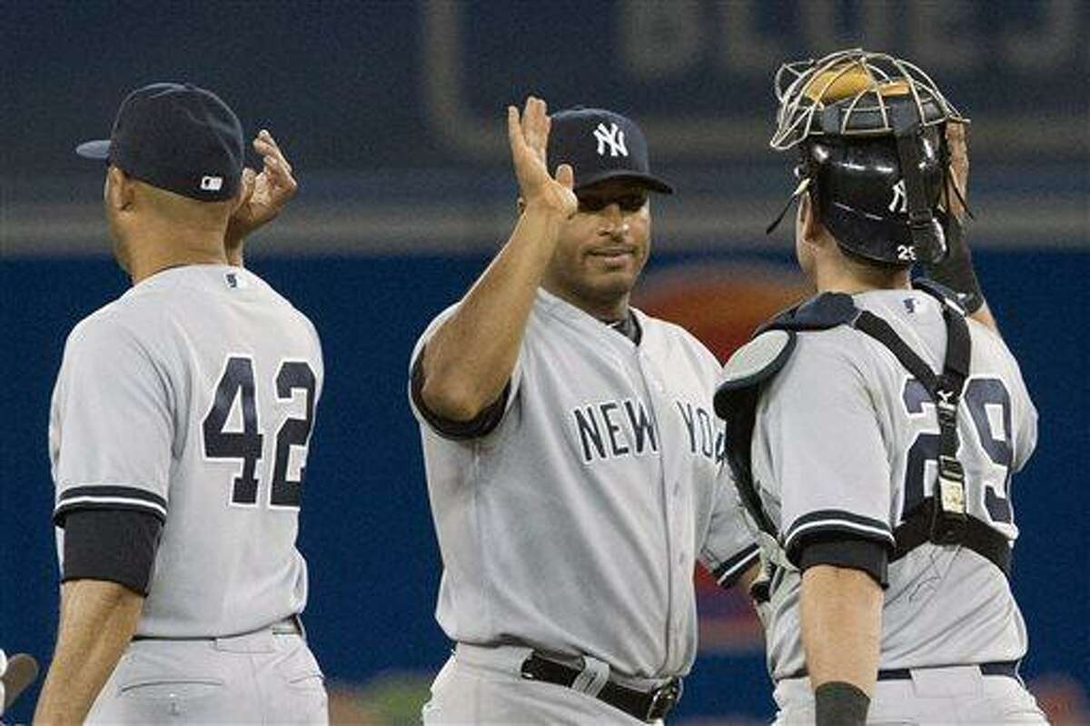 New York Yankees' Vernon Wells, center, celebrates with teammates Mariano Rivera, left, and Francisco Cerveili after defeating the Toronto Blue Jays 5-3 in a baseball game in Toronto, Saturday, April 20, 2013. (AP Photo/The Canadian Press, Chris Young)