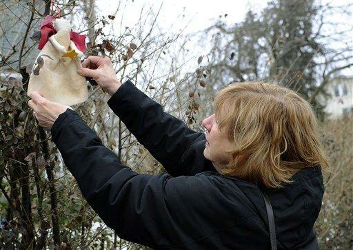 In this Tuesday, Feb. 5, 2013 photo, Teresa Rousseau, mother of Sandy Hook Elementary School victim Lauren Rousseau, straightens out a sewn angel left in a bush by a stranger outside her home in Danbury, Conn. Teacher Lauren Rousseau, 30, was one of 26 people killed in the Dec. 14, 2012 massacre at Sandy Hook Elementary School in Newtown, Conn. Lauren Rousseau will be one of six educators from the school honored posthumously with the 2012 Presidential Citizens Medal, presented at a White House ceremony on Feb. 15. (AP Photo/Jessica Hill)
