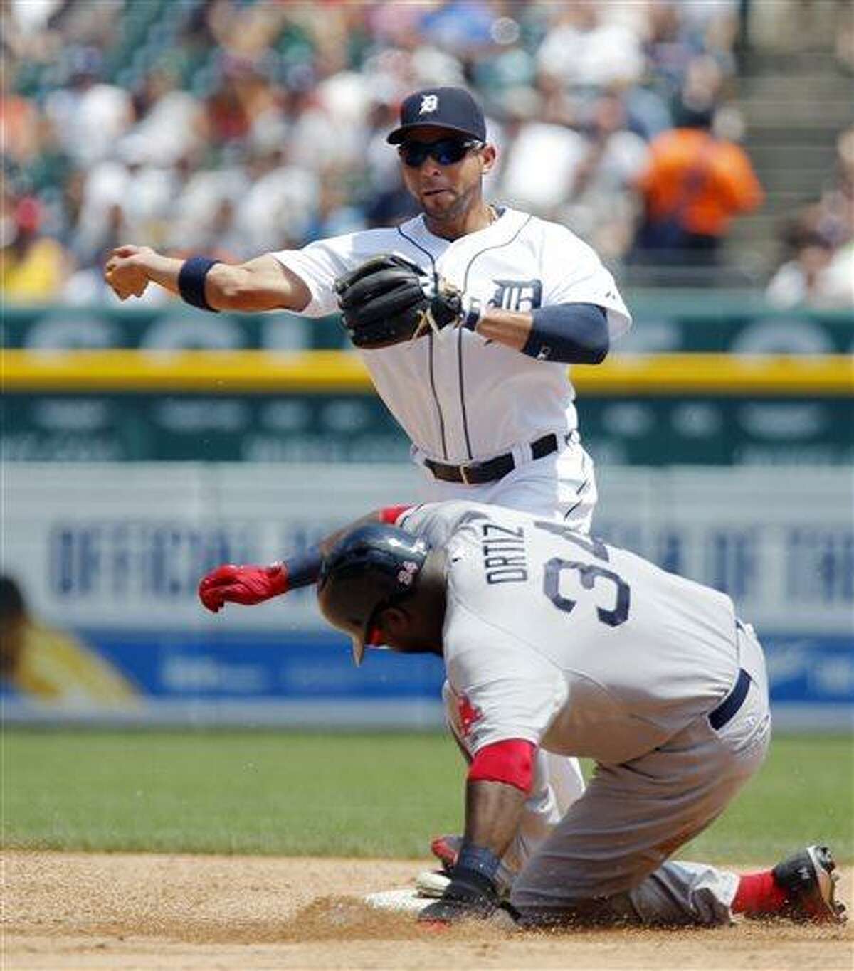 Detroit Tigers second baseman Omar Infante, top, turns the ball after getting a force-out on Boston Red Sox's David Ortiz (34) in the third inning of a baseball game on Sunday, June 23, 2013, in Detroit. Infante's throw was wild to first base and Red Sox's Mike Napoli was safe on the play. (AP Photo/Duane Burleson)