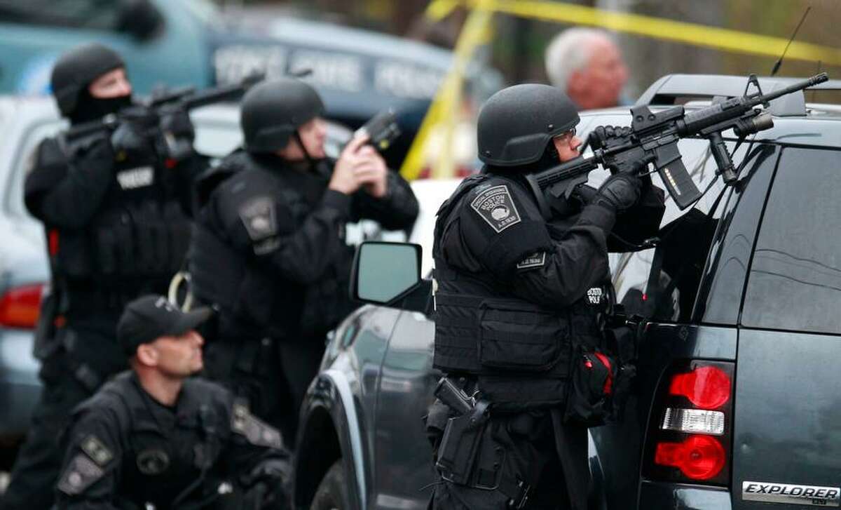 Police in tactical gear surround an apartment building while looking for a suspect in the Boston Marathon bombings in Watertown, Mass., Friday, April 19, 2013. All residents of Boston were ordered to stay in their homes Friday morning as the search for the surviving suspect in the marathon bombings continued after a long night of violence that left another suspect dead. (AP Photo/Charles Krupa)