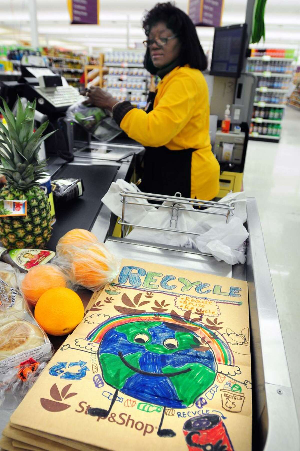 Cashier Valerie Ingram scans items at the Super Stop & Shop in Hamden on 4/12/2013. The stack of bags in the foreground were decorated by Hamden students to promote the Hamden Earth Day Celebration at Hamden Middle School on April 20th.Photo by Arnold Gold/New Haven Register AG0492C