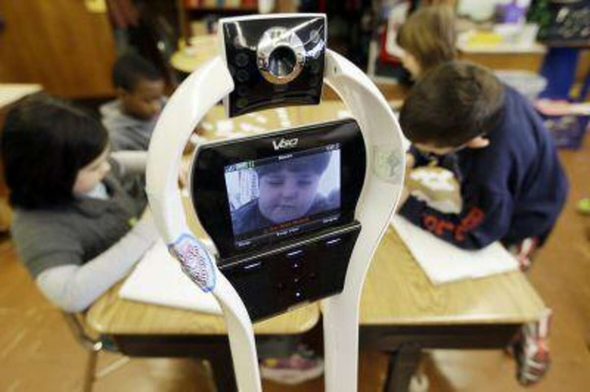 In this Thursday, Jan. 24, 2013 photo, Devon Carrow attends Winchester Elementary School from home while operating a robot in the classroom, in West Seneca N.Y. Carrow's life-threatening allergies don't allow him to go to school. But the 4-foot-tall robot with a wireless video hookup gives him the school experience remotely, allowing him to participate in class, stroll through the hallways, hang out at recess and even take to the auditorium stage when there's a show. (AP Photo/David Duprey)