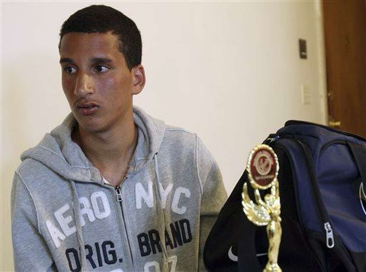 Salah Eddin Barhoum sits in his apartment in Revere, Mass., Thursday, April 18, 2013, with one of the trophies he won in an athletic competition, and the bag he was carrying on Monday near the finish line of the Boston Marathon. The 17-year-old from Morocco, whose photograph appeared on the front page of the New York Post in connection with the Boston Marathon bombings, told The Associated Press he has been scared to go outside because he worries people will blame him for Monday's attack. (AP Photo/Rodrique Ngowi)