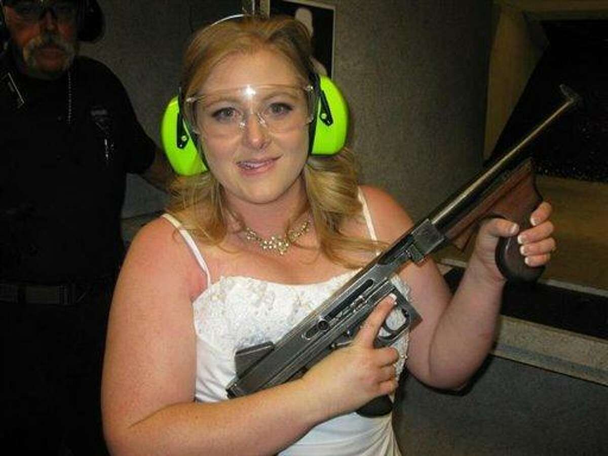 This July 28, 2012 photo provided by Bob MacDuff shows Lindsae MacDuff holding an automatic weapon at the Gun store in Las Vegas after her "shotgun wedding." One Las Vegas shooting range is selling "take a shot at love" packages that include 50 submachine gun rounds. Another is offering wedding packages in which the bride and groom can pose with Uzis and ammunition belts. And a third invites lovebirds to renew their vows and shoot a paper cutout zombie in the face. (AP Photo/Bob MacDuff)