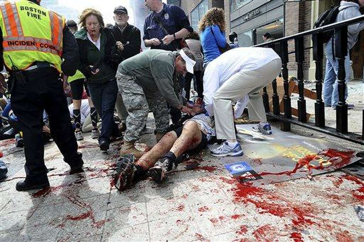 In this April 15, 2013 photo, an injured person is helped on the sidewalk near the Boston Marathon finish line following an explosion in Boston. The bombs that made Boston look like a combat zone have also brought battlefield medicine to their civilian victims. A decade of wars in Iraq and Afghanistan has sharpened skills and scalpels, leading to dramatic advances that are now being used to treat the 13 amputees and nearly a dozen other patients still fighting to keep damaged limbs. (AP Photo/MetroWest Daily News, Ken McGagh, File) MANDATORY CREDIT