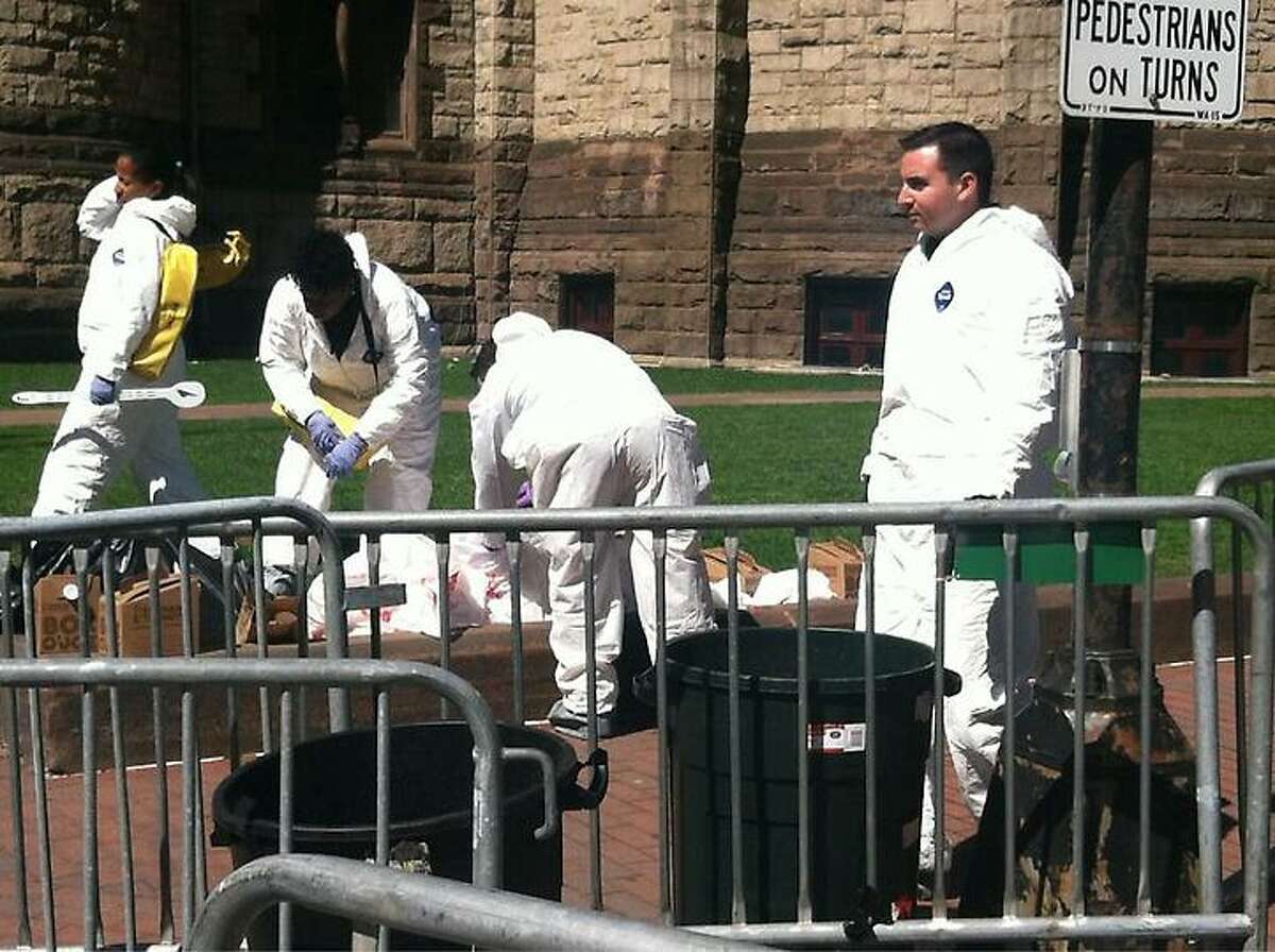 Workers in white suits carefully pick through leftovers from the race Wednesday. Jennifer Swift/Register
