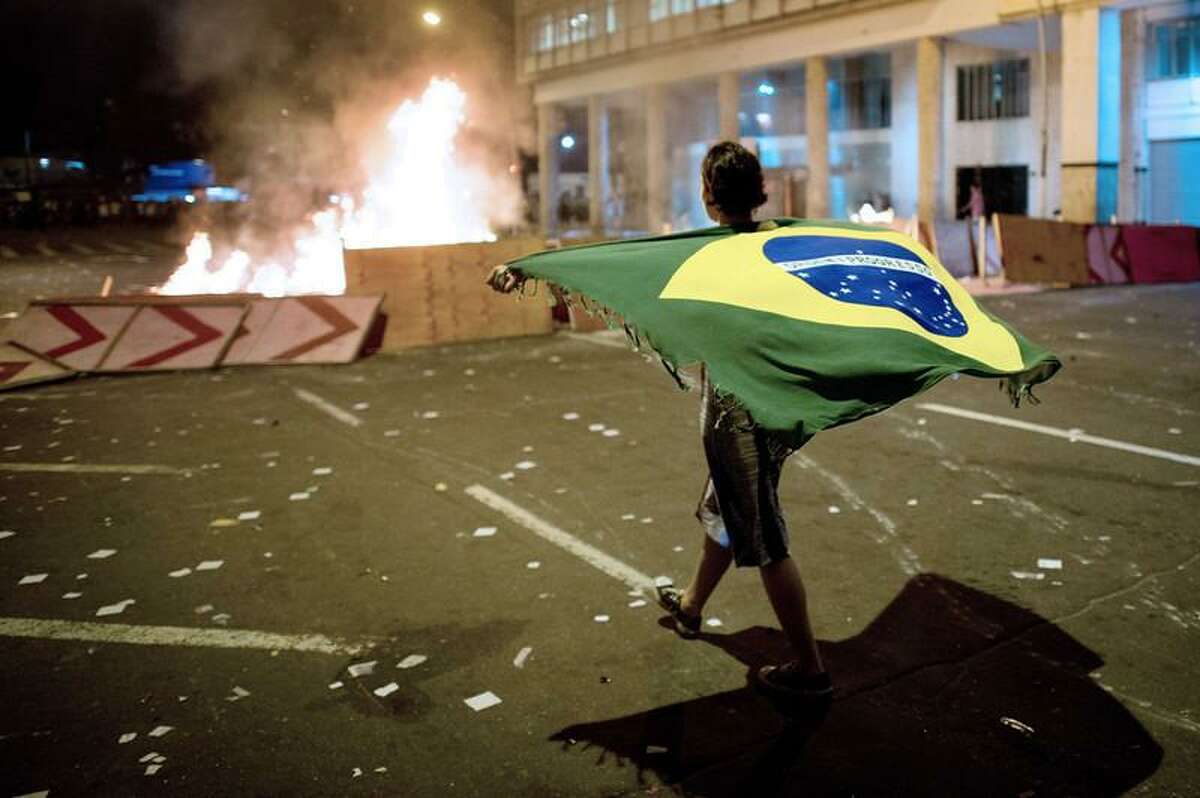 A demonstrator walks with a Brazilian flag late on June 19, 2013 in the center of Niteroi, 10 kms from Rio de Janeiro. Protesters battled police late on June 19, even after Brazil's two biggest cities rolled back the transit fare hikes that triggered two weeks of nationwide protests. The fare rollback in Sao Paulo and Rio de Janeiro marked a major victory for the protests, which are the biggest Brazil has seen in two decades. CHRISTOPHE SIMON/AFP/Getty Images