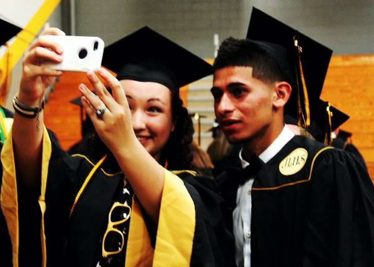Left, Asia Cowby and right, Andres Navarro take pictures before the Jonathon Law graduation ceremony in Milford on 06/20/2013. Nicole Dellolio/ For the Register
